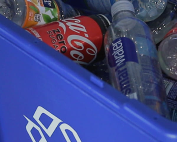 Un bac de recyclage bleu contenant des bouteilles en plastique et des canettes