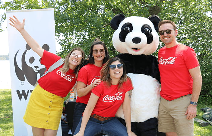Un groupe d'employés de Coca-Cola devant une mascotte représentant un panda