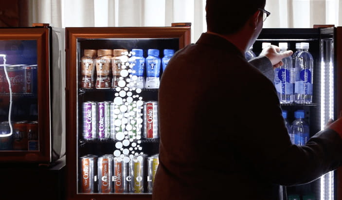 Un homme devant un frigo ouvert et prenant une bouteille d'eau
