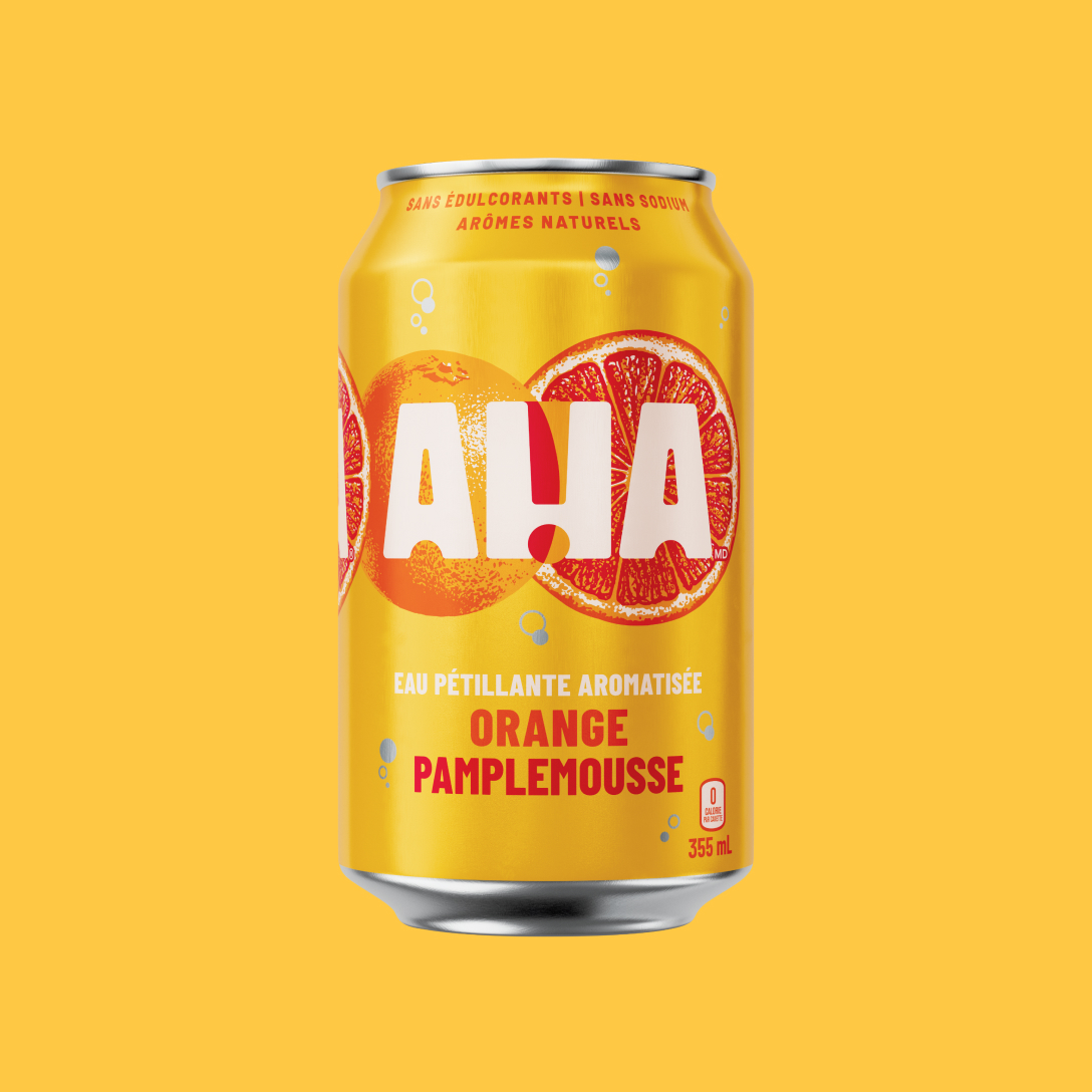 Une canette jaune doré de 355 mL d'eau pétillante aromatisée AHA orange et pamplemousse. Derrière le logo blanc AHA, on voit une orange et une tranche de pamplemousse illustrées. La canette indique « Sans édulcorants | Sans sodium | Arômes naturels » et « 0 calorie par canette ». Elle est présentée sur un fond jaune assorti.