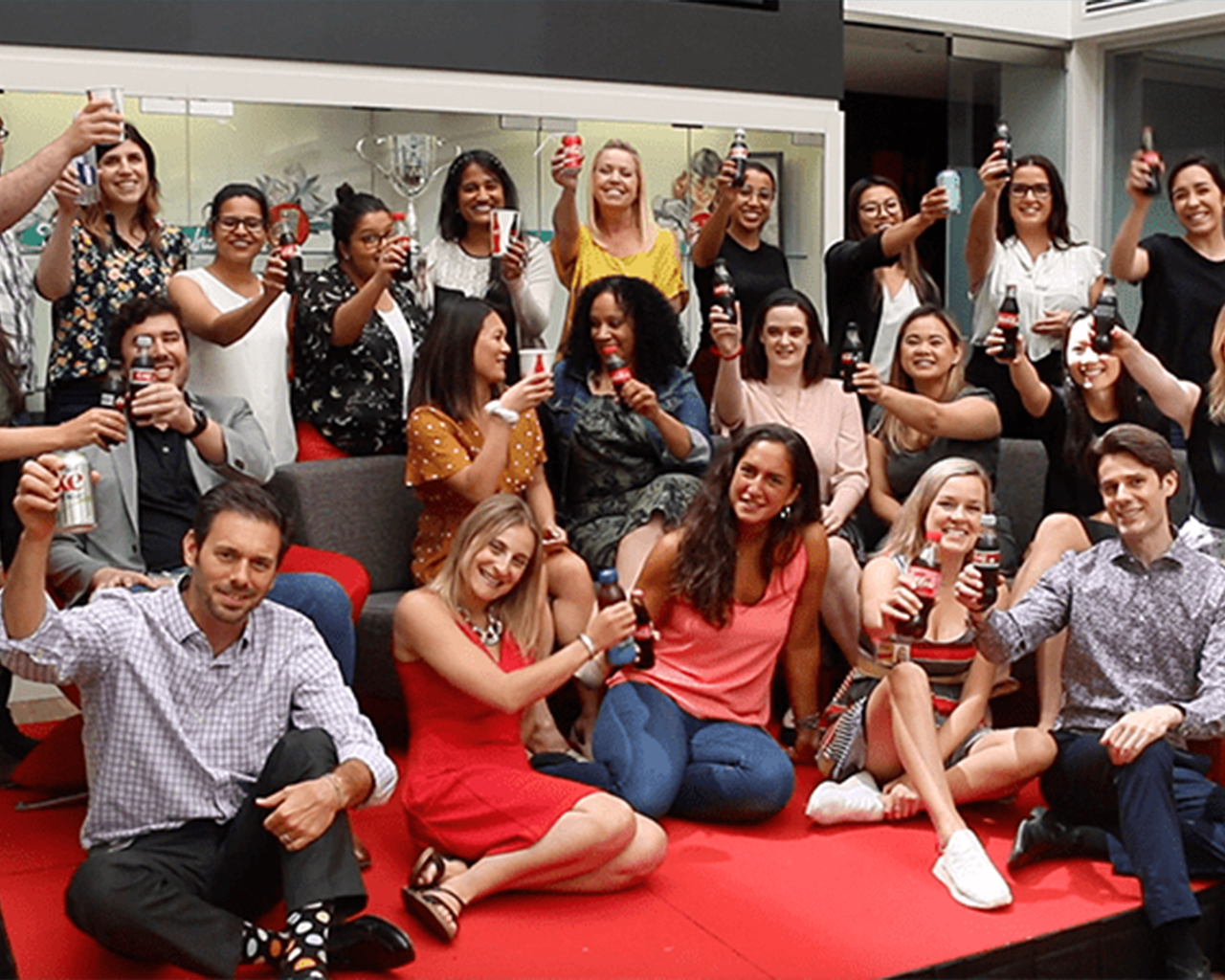  Un groupe de personnes heureuses présentant des boissons Coca-Cola dans leurs mains