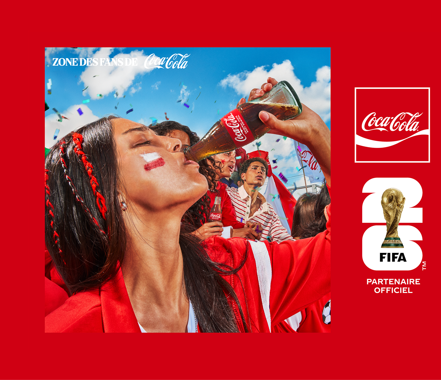 Fans in red celebrating at Coca-Cola FIFA Fan Zone, woman raising a Coke bottle amid confetti and FIFA World Cup branding.