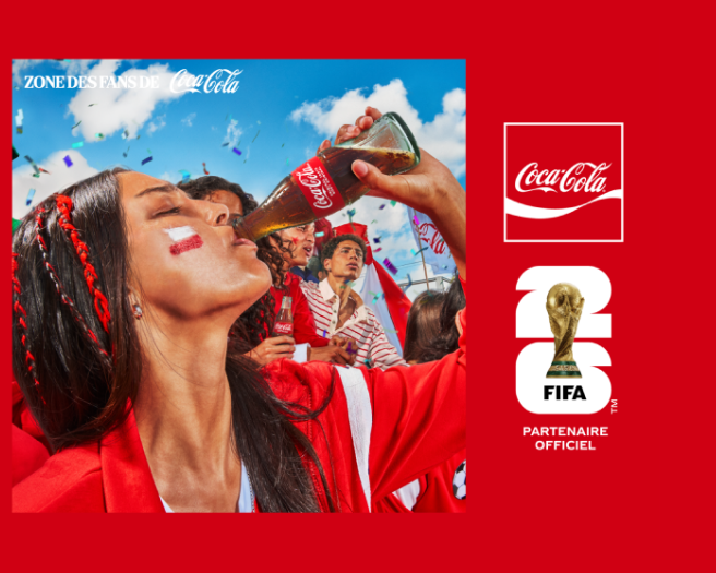 Fans in red celebrating at Coca-Cola FIFA Fan Zone, woman raising a Coke bottle amid confetti and FIFA World Cup branding.