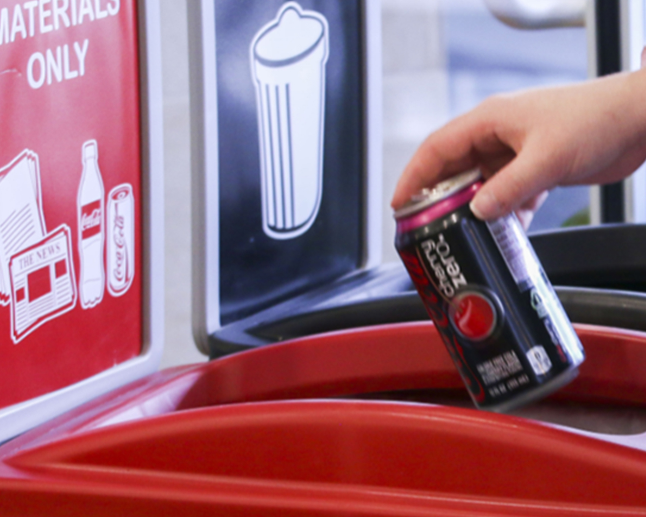 Un homme met une canette de Coca-Cola vide dans la poubelle de recyclage