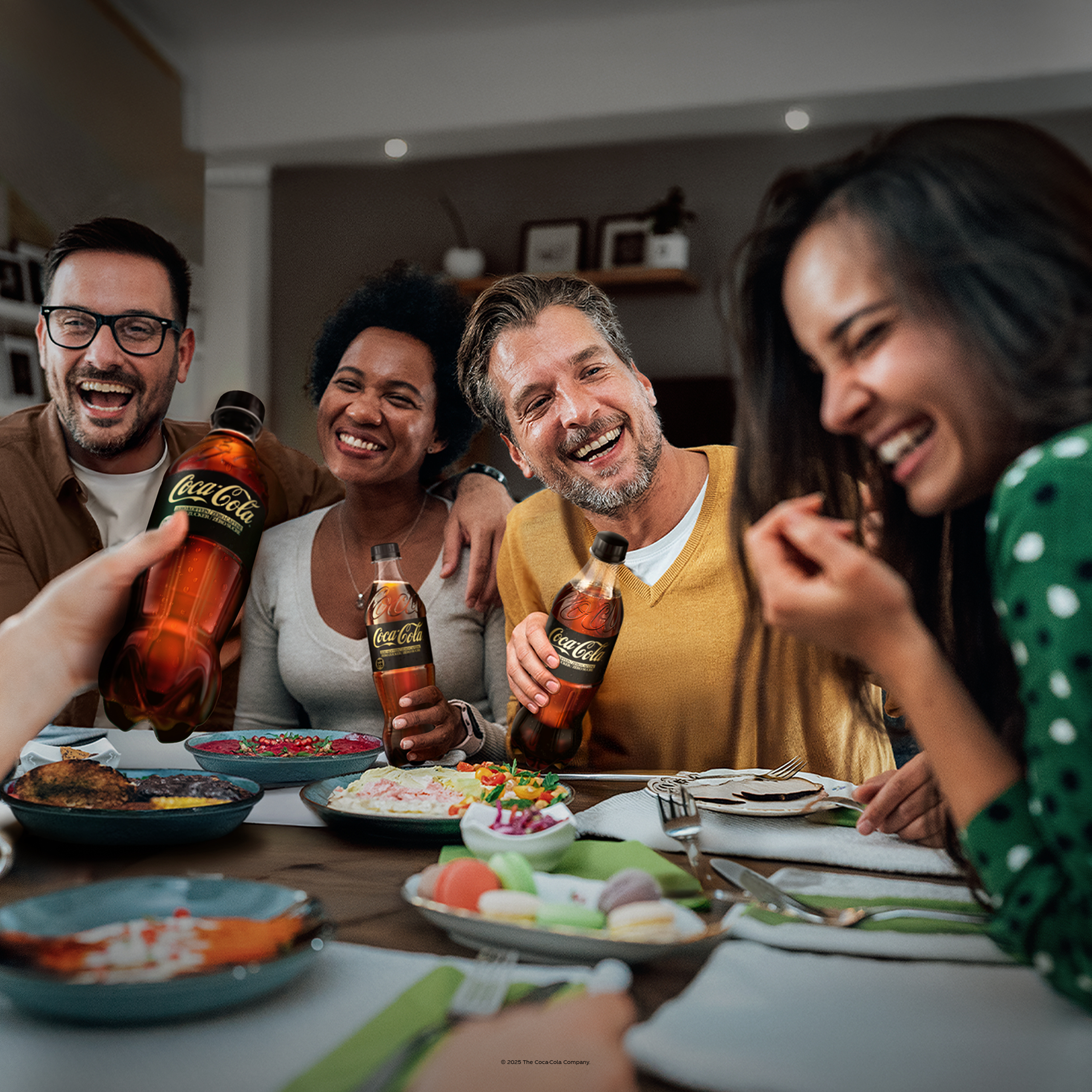 Lächelnde Menschen sitzen zusammen und genießen ein Abendessen mit Coca-Cola Zero Zucker.
