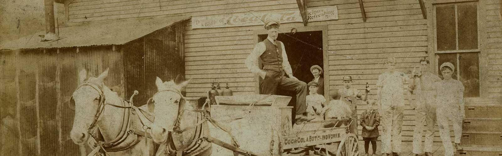 Un homme dans une calèche avec des personnes en arrière-plan en train de boire du Coca-Cola.