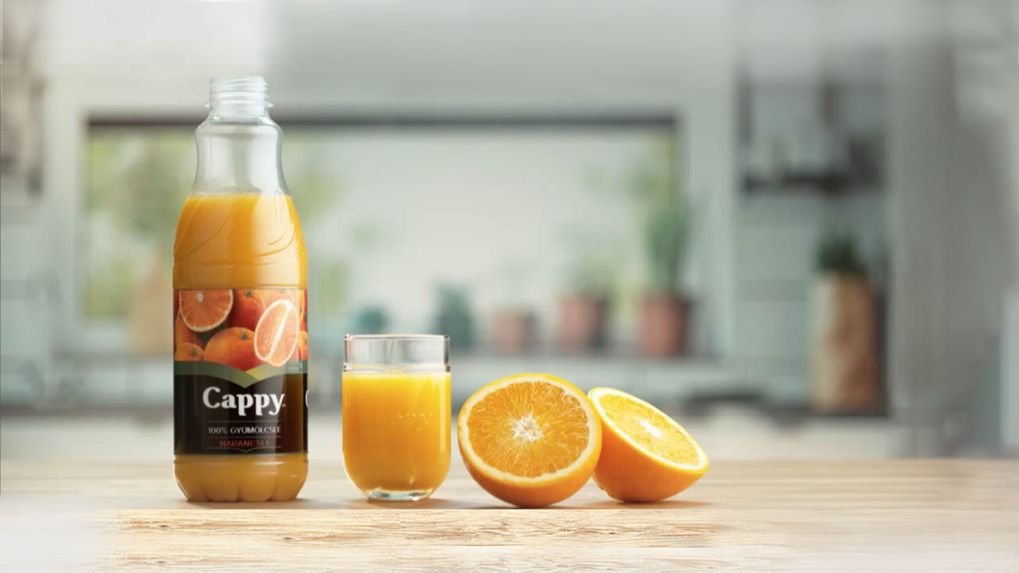 Eine Flasche Cappy Orangensaft, neben einem gefülltem Glas und einer halbierten Orange.