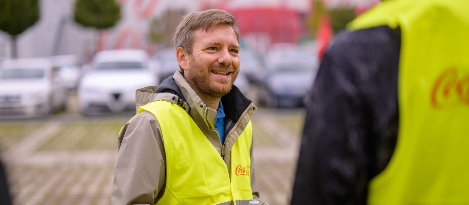 homme souriant portant une veste jaune coca-cola