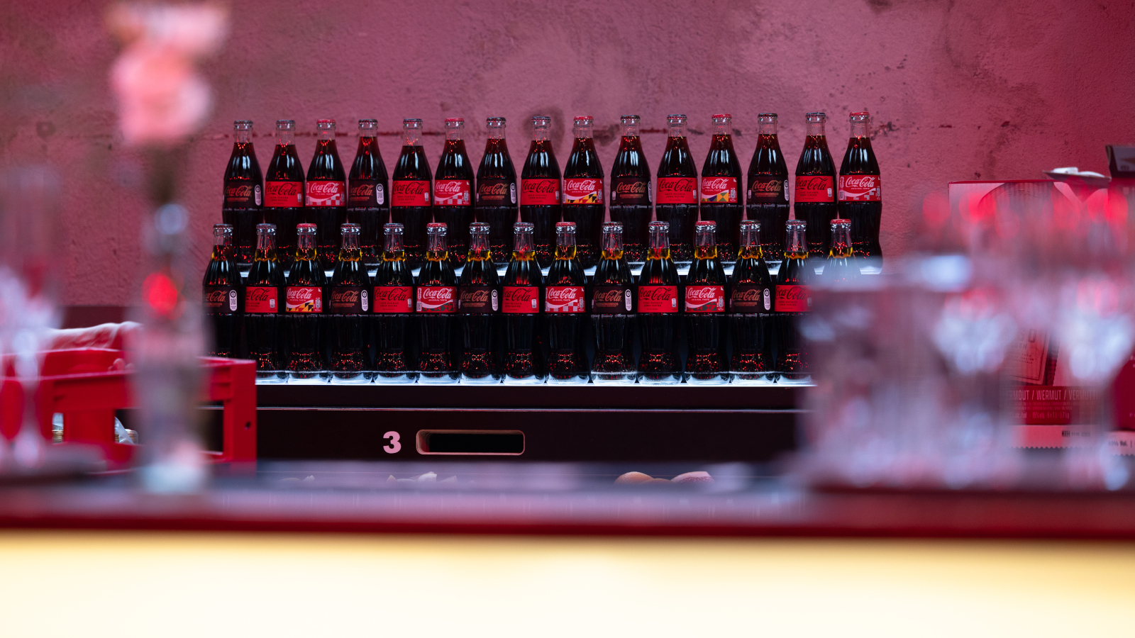 Des bouteilles en verre Coca-Cola devant un fond rouge lors de la fête du jubilé.