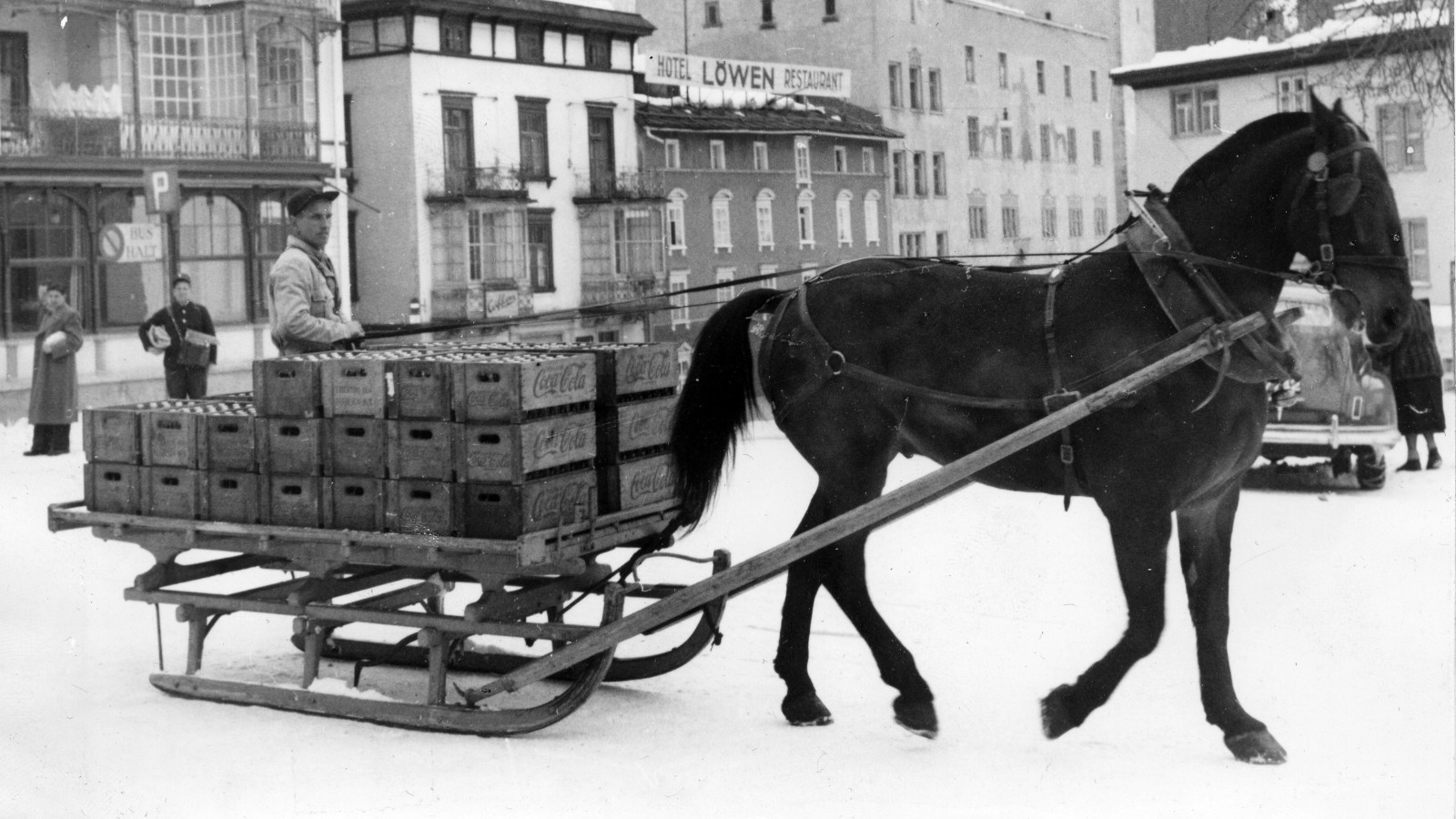 Photo historique d’un attelage transportant des caisses de bouteilles Coca-Cola dans une ville suisse.