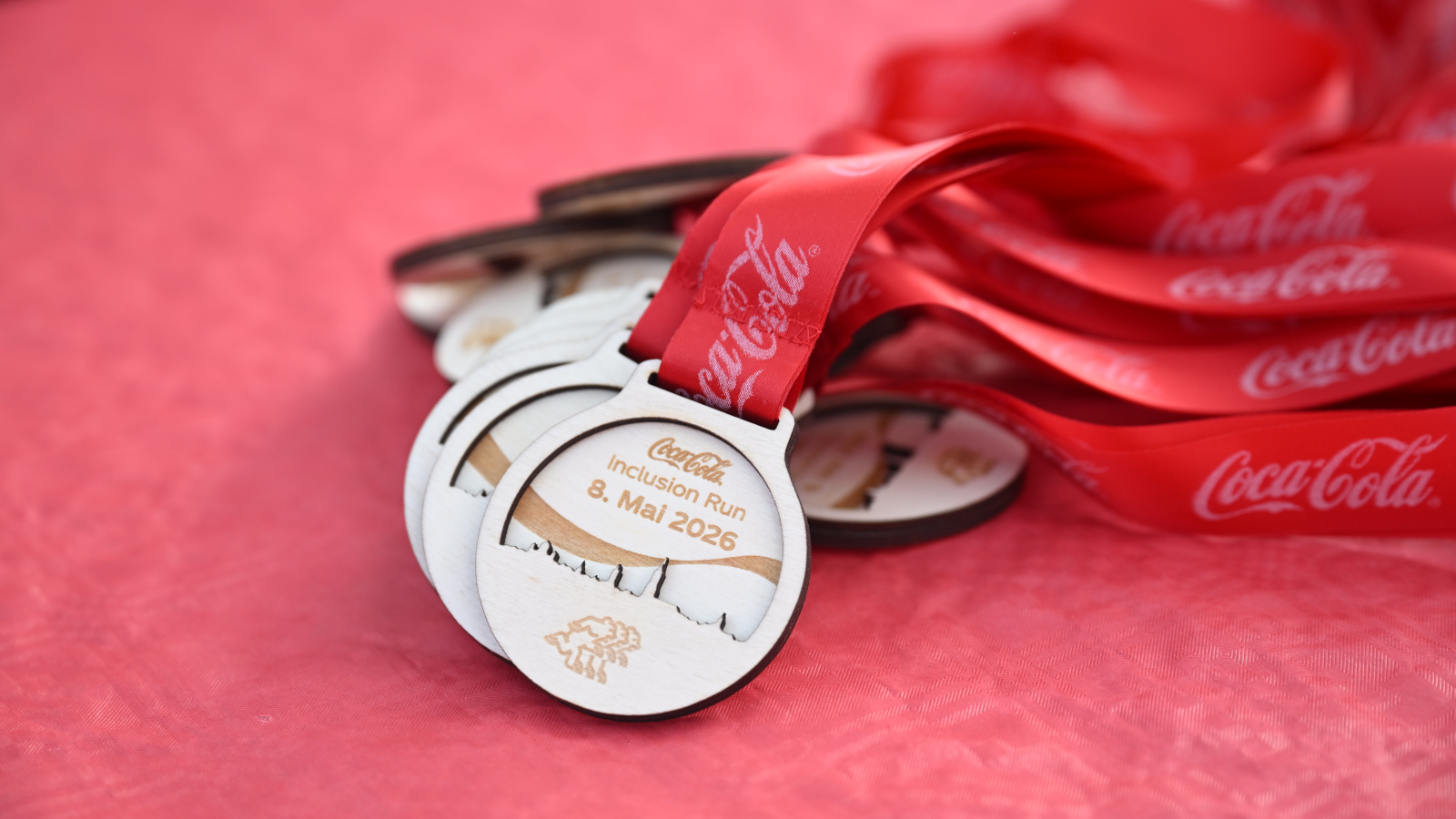 Die Medaillen des Coca-Cola Inclusion Run auf rotem Hintergrund