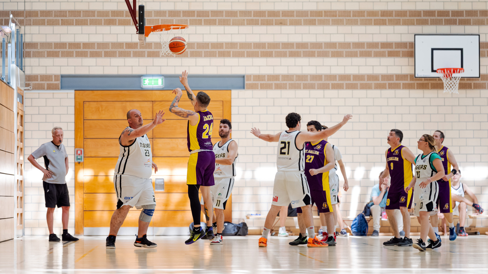 Des athlètes jouent au basketball dans une salle.