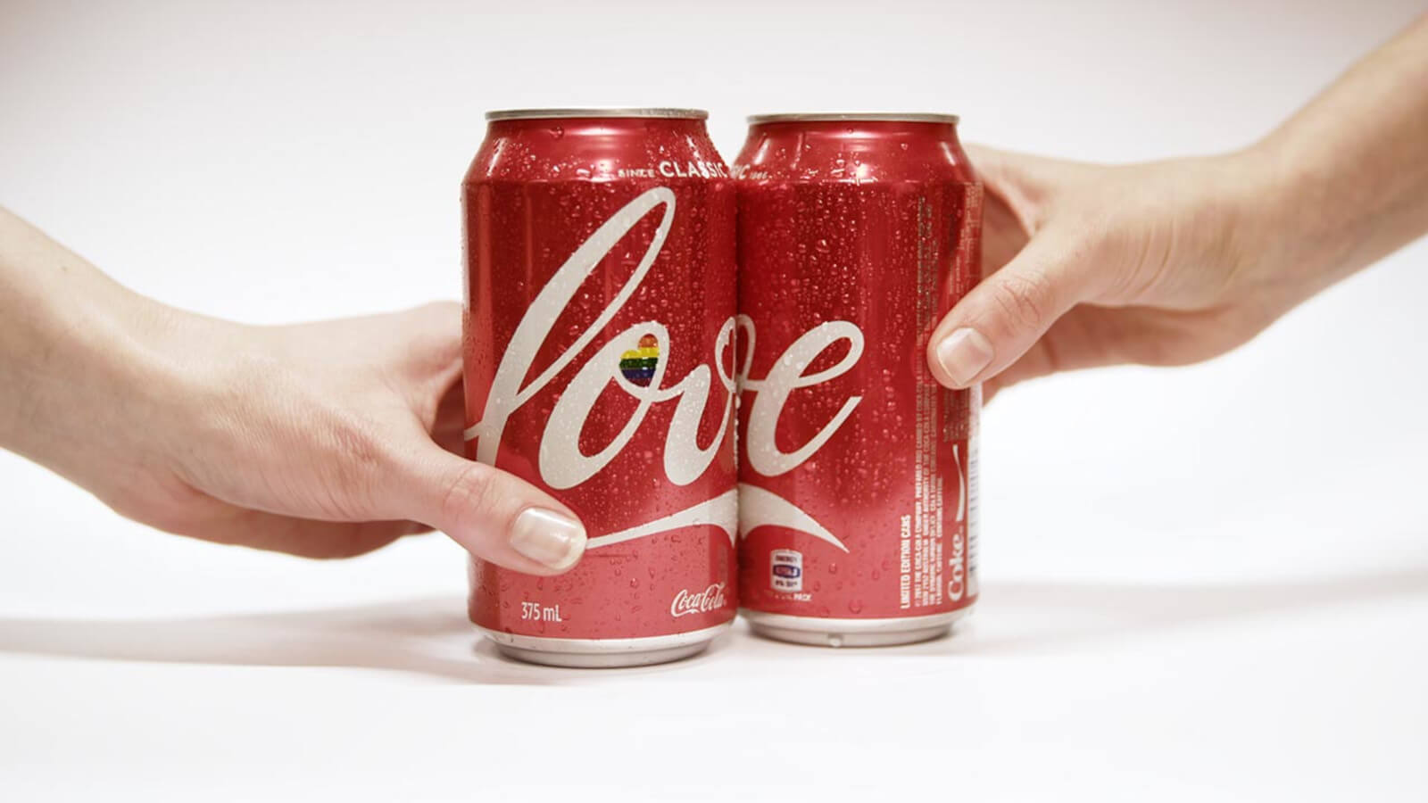 Zwei Hände halten Coca-Cola Love Cans
