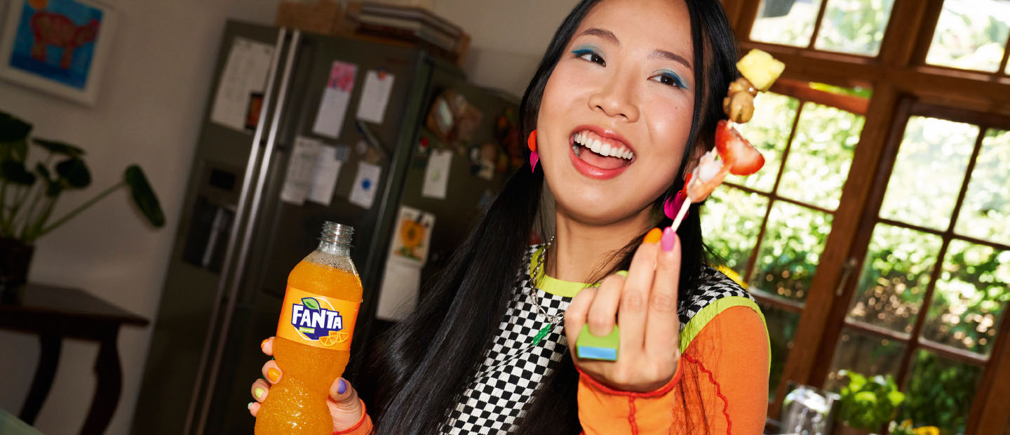 Woman with bottle of Fanta and fruit on a cocktail stick