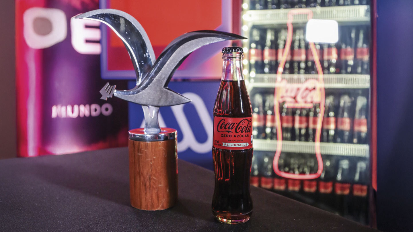 Trofeo del Festival Viña del Mar junto a una botella de Coca-Cola Zero. De fondo una heladera con botellas de Coca-Cola.