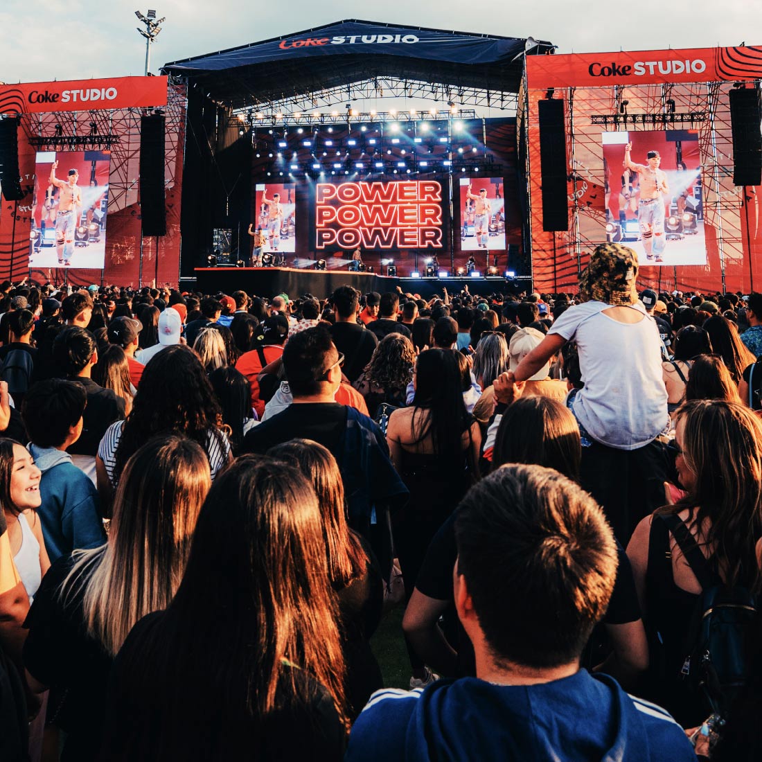 "Multitud en un concierto de Coke Studio Chile, con el escenario iluminado y pantallas mostrando 'POWER' al fondo