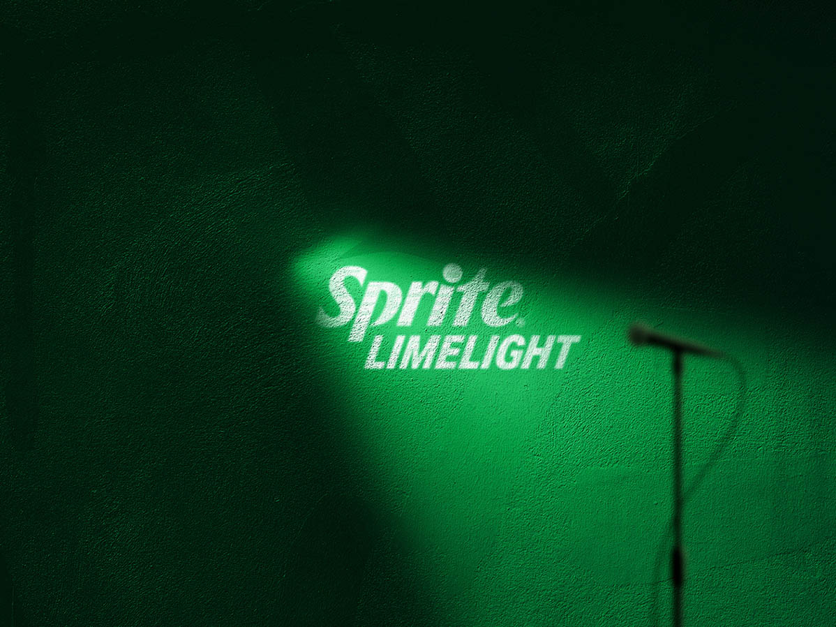 Reflector iluminando una pared verde con la frase: Sprite limelight. Acompañado de la silueta de un micrófono. 