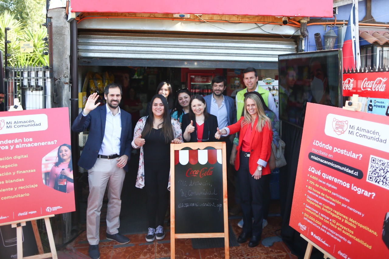 Foto de varias personas frente a un local, saludando a la cámara.