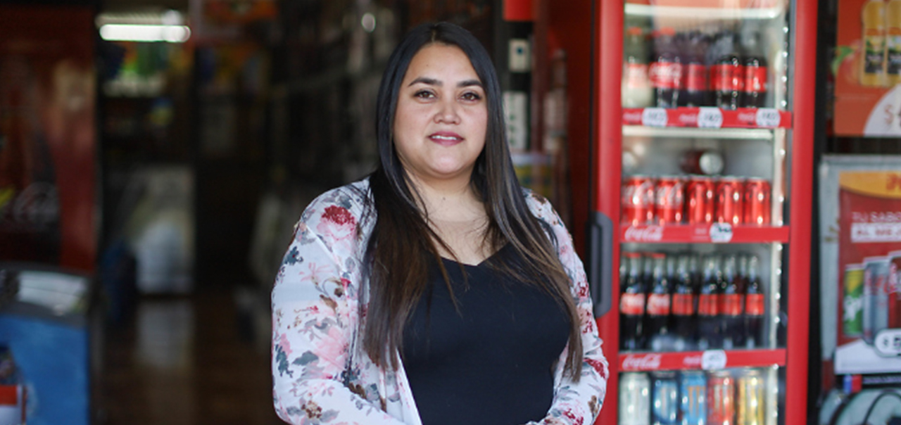 Mujer parada frente a una hielera con productos Coca-Cola.