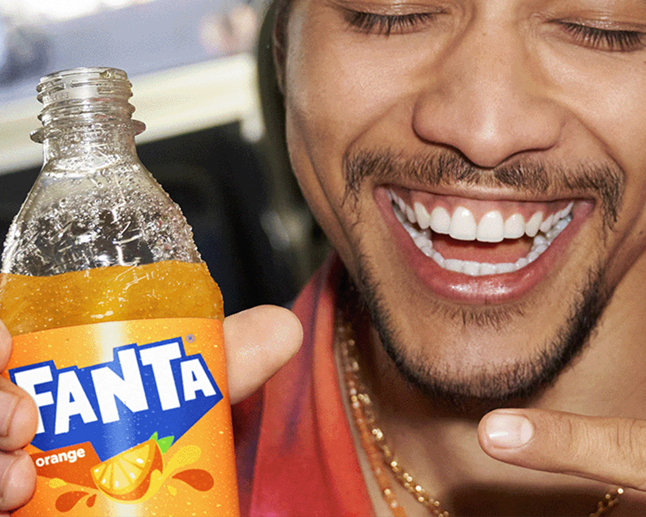 Hombre sonriendo con una botella de Fanta en la mano