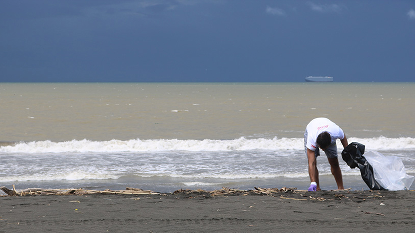 Persona recogiendo residuos en una playa