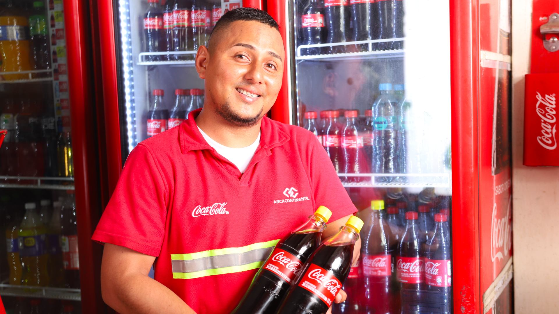 Trabajador de Coca-Cola con una remera roja y dos botellas de Coca-Cola en las manos