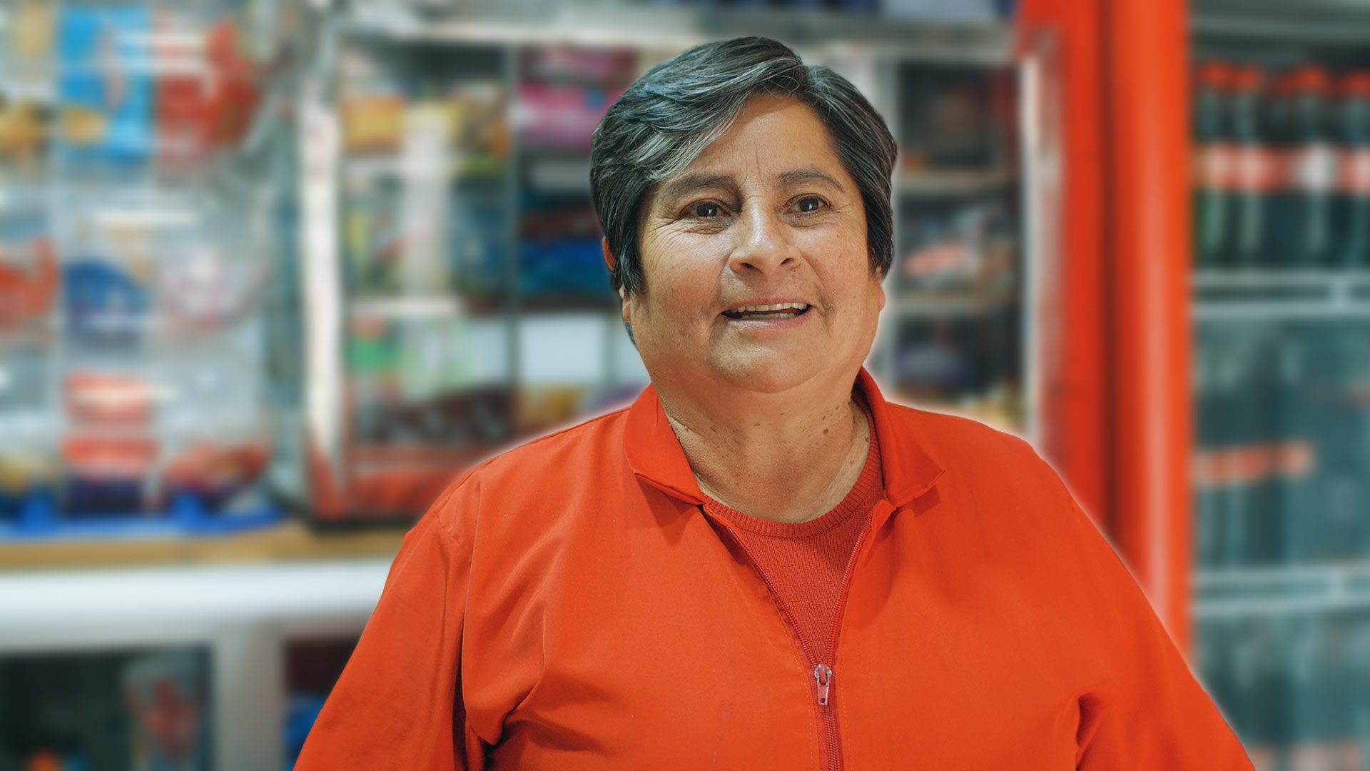 Mujer sonriendo vestida de color naranja de fondo hay productos coca-cola
