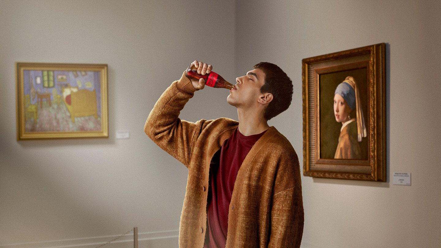 Un hombre bebiendo Coca-Cola en una botella de vidrio