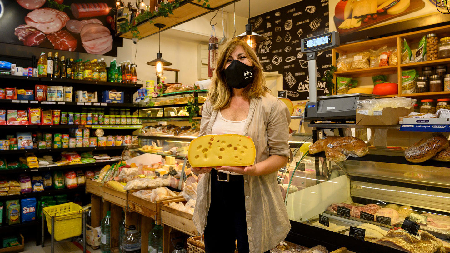 Mujer sosteniendo un queso en una tienda de comestibles