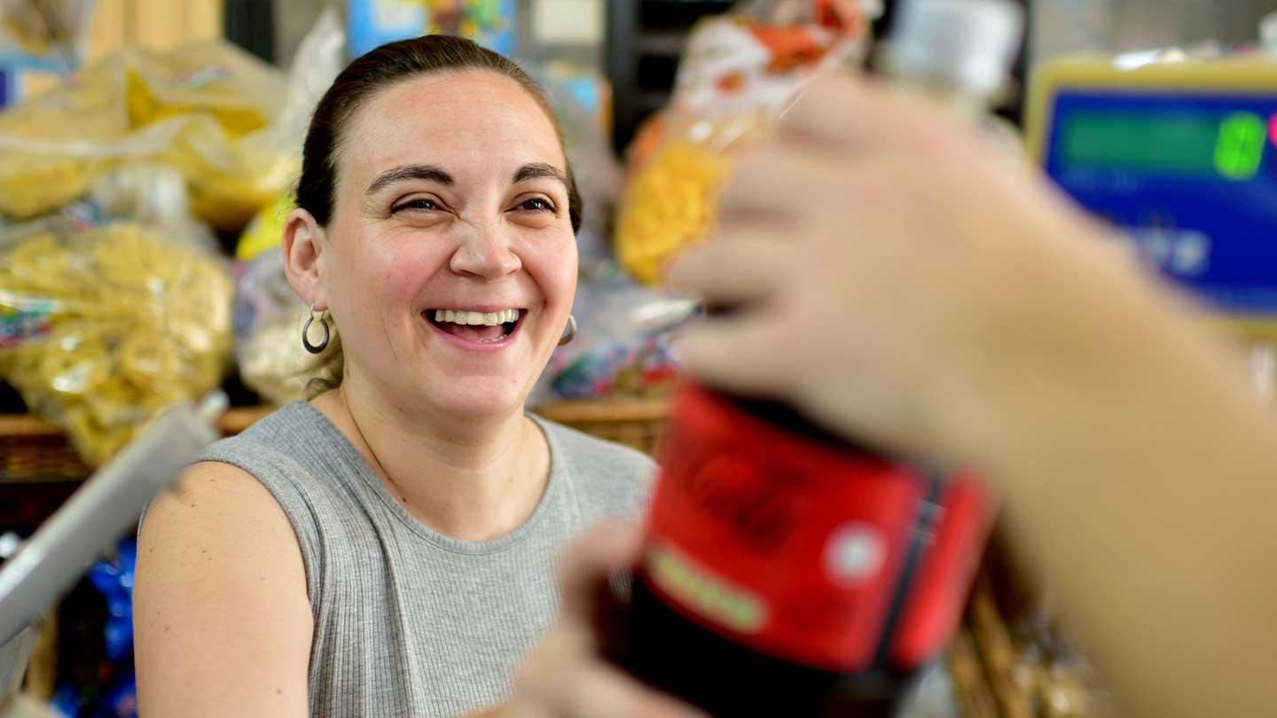 Botella de Coca-Cola con mujer riendo de fondo en una tienda