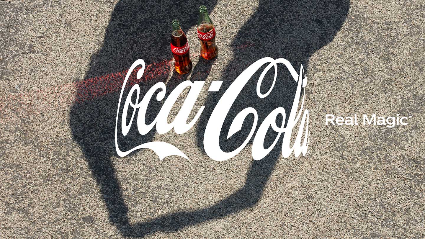 Dos botellas de Coca-Cola junto al logo Coca-Cola Real Magic