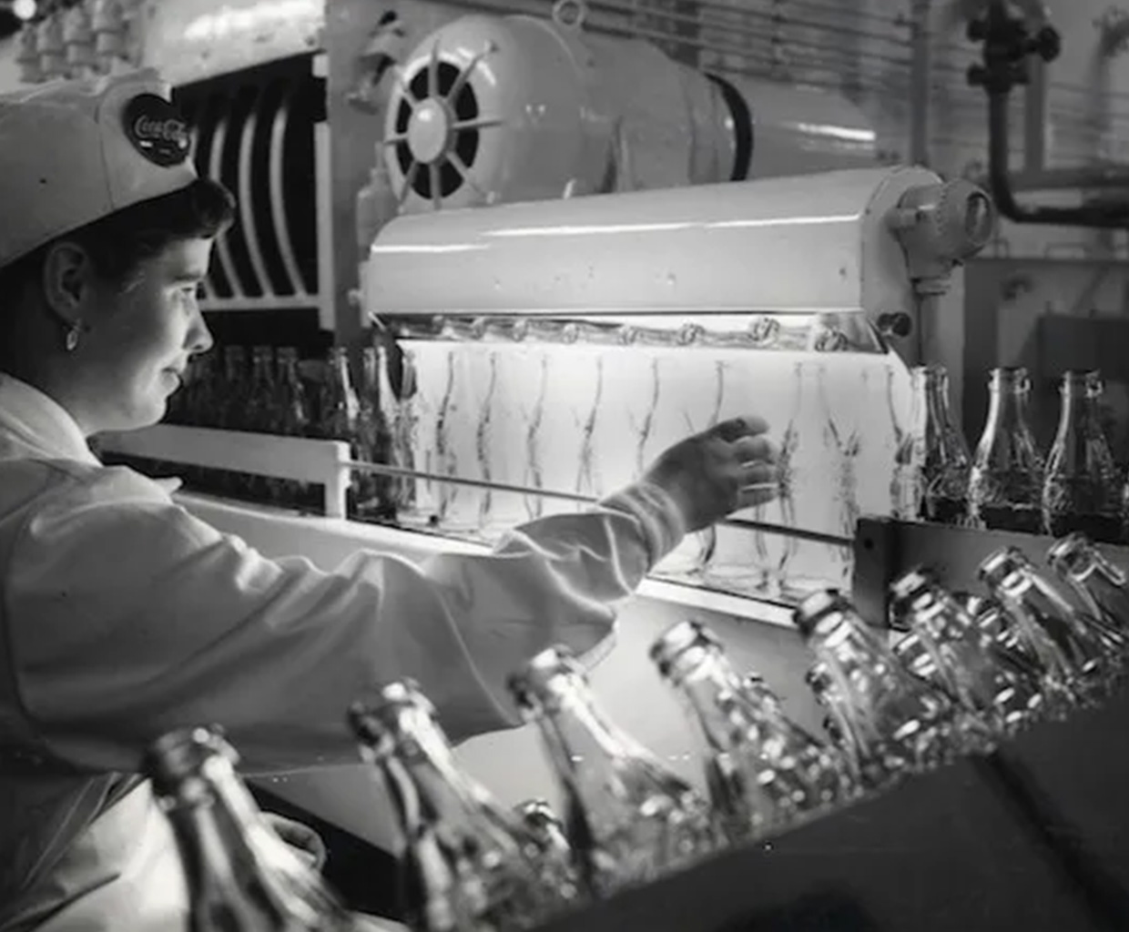 Foto en blanco y negro de una mujer trabajando en una fabrica de Coca-Cola