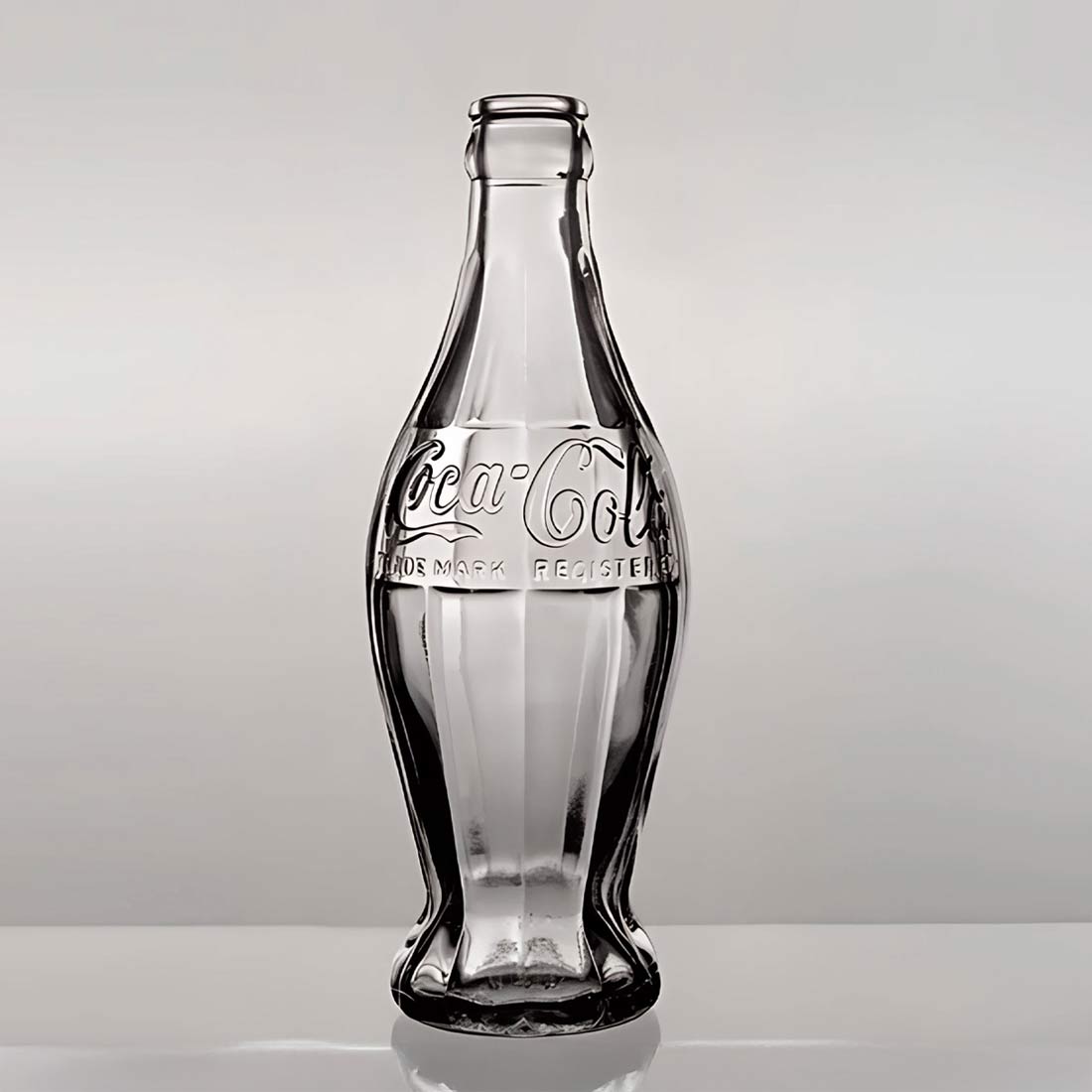 Botella de vidrio Coca-Cola vacía sobre un fondo claro