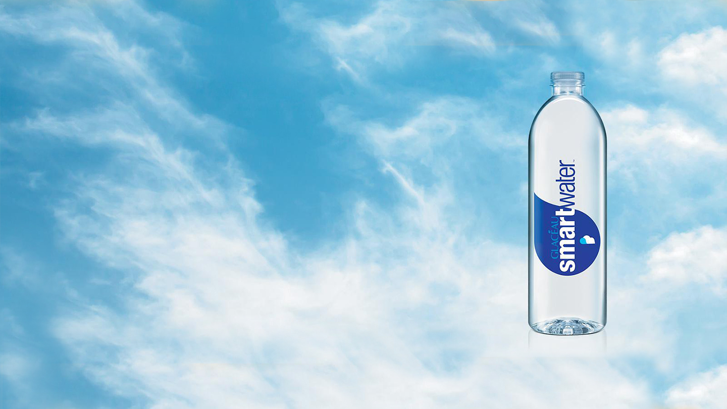 Glacéau Smartwater voda ve skleněné lahvi s pozadím nebe