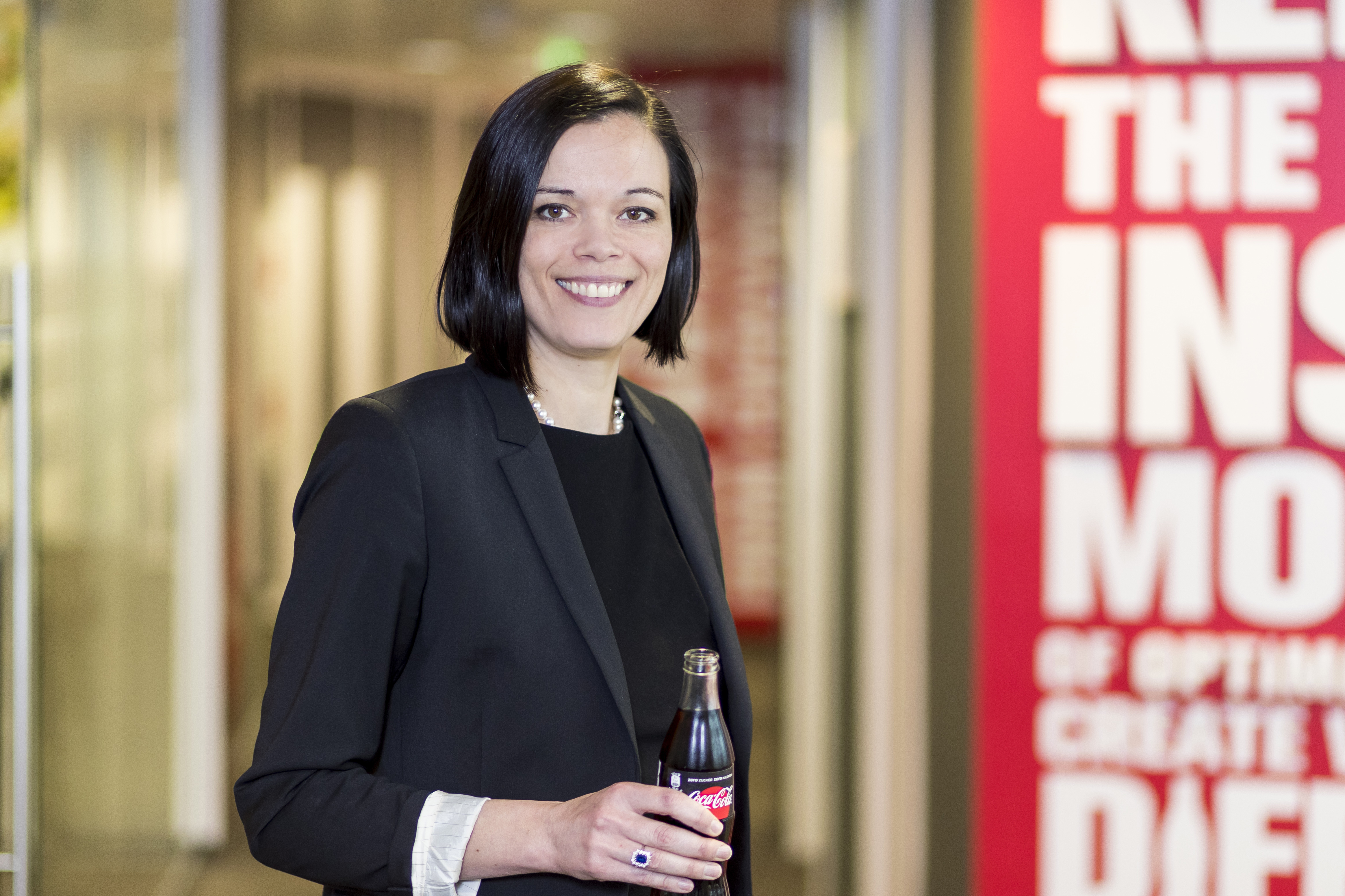 Eine lächelnde Frau mit einer Flasche Coca-Cola in der Hand