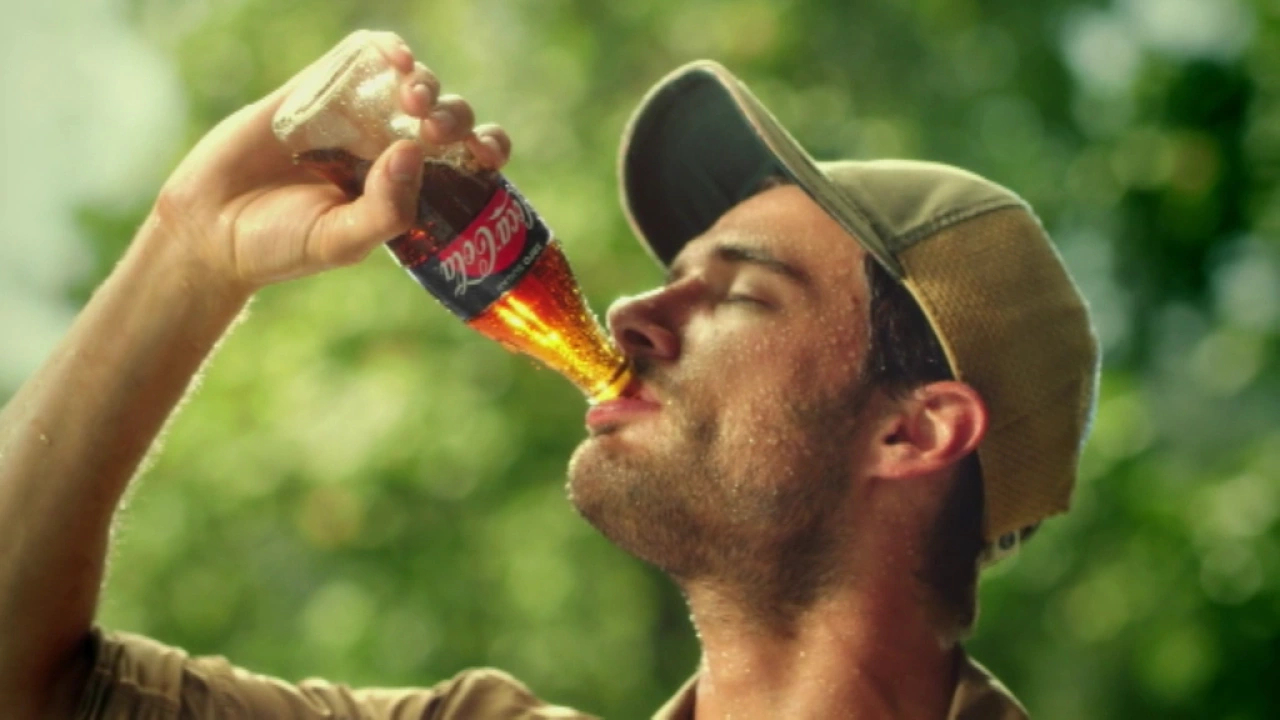 Video-Standbild, auf dem ein Mann aus einer Flasche Coca-Cola trinkt.