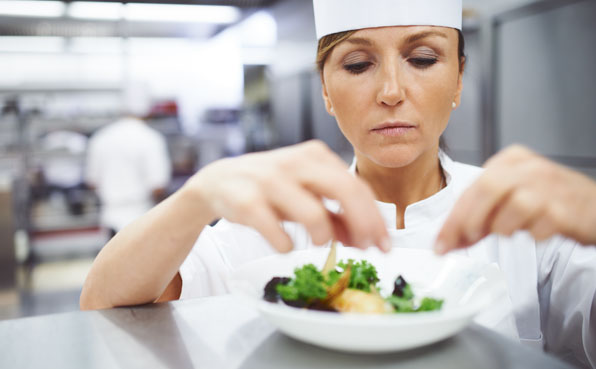 Eine Restaurantköchin, die ein Gericht in einem Teller anrichtet