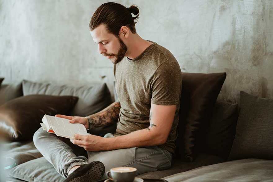 Ein Mann sitzt auf einem Sofa und liest in einem Buch.