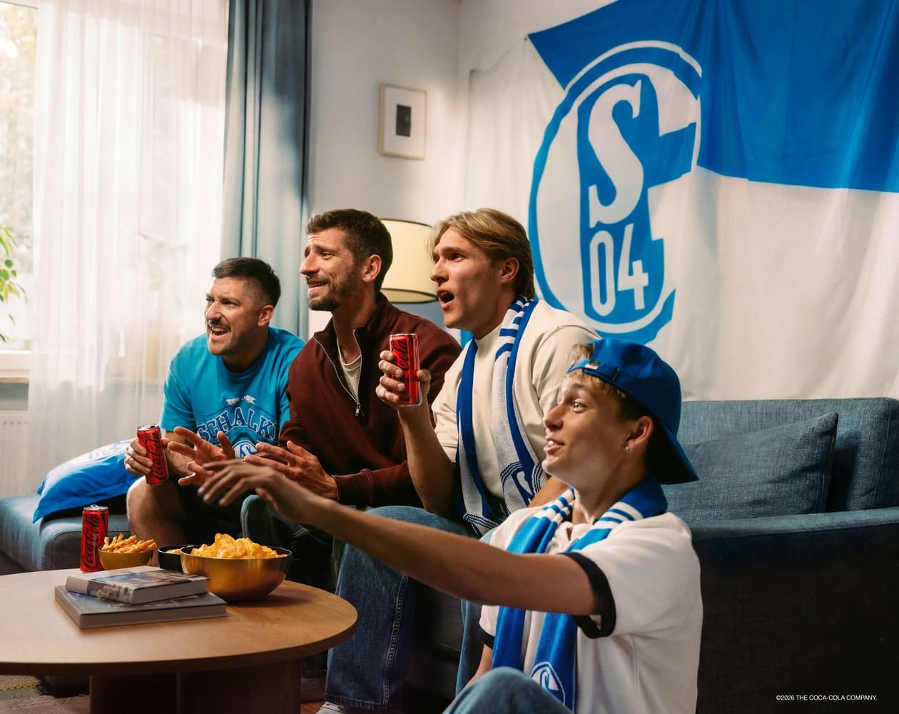 Begeisterte Menschen schauen Sport und trinken Coca-Cola.