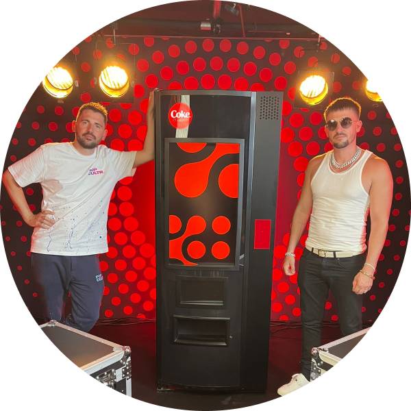 Zwei Männer neben einem Coke-Automaten