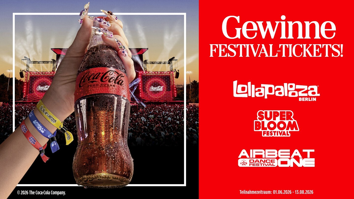Eine Hand hält eine Coca-Cola-Flasche auf einem Musikfestival.