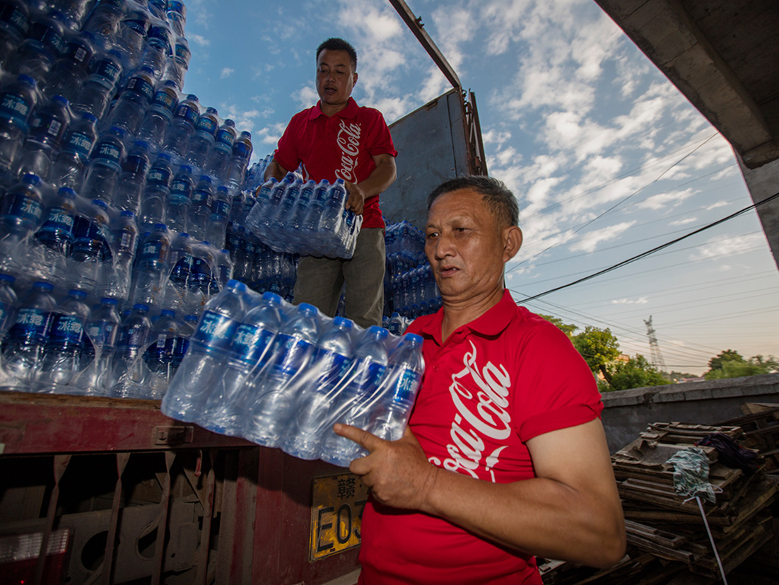 Deux hommes déchargent des paquets d'eau en bouteille d'un camion