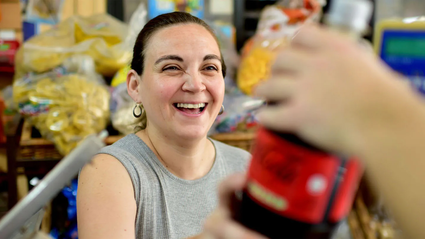 Una mujer alegre con una brillante sonrisa comprando una bebida Coca-Cola