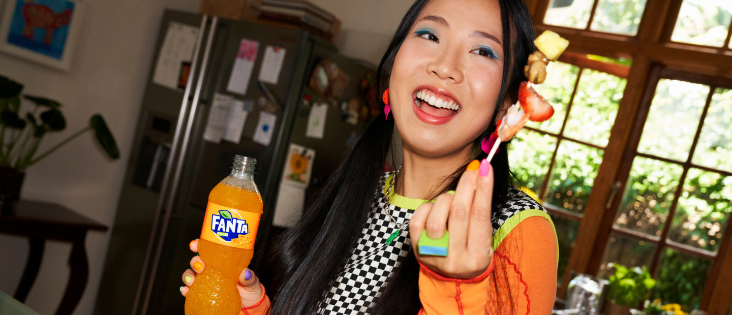 Woman with bottle of Fanta and fruit on a cocktail stick