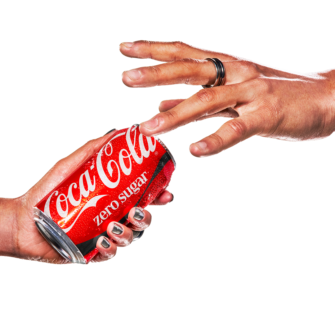 Roka tur sarkanu Coca-Cola Zero Sugar bundžu.