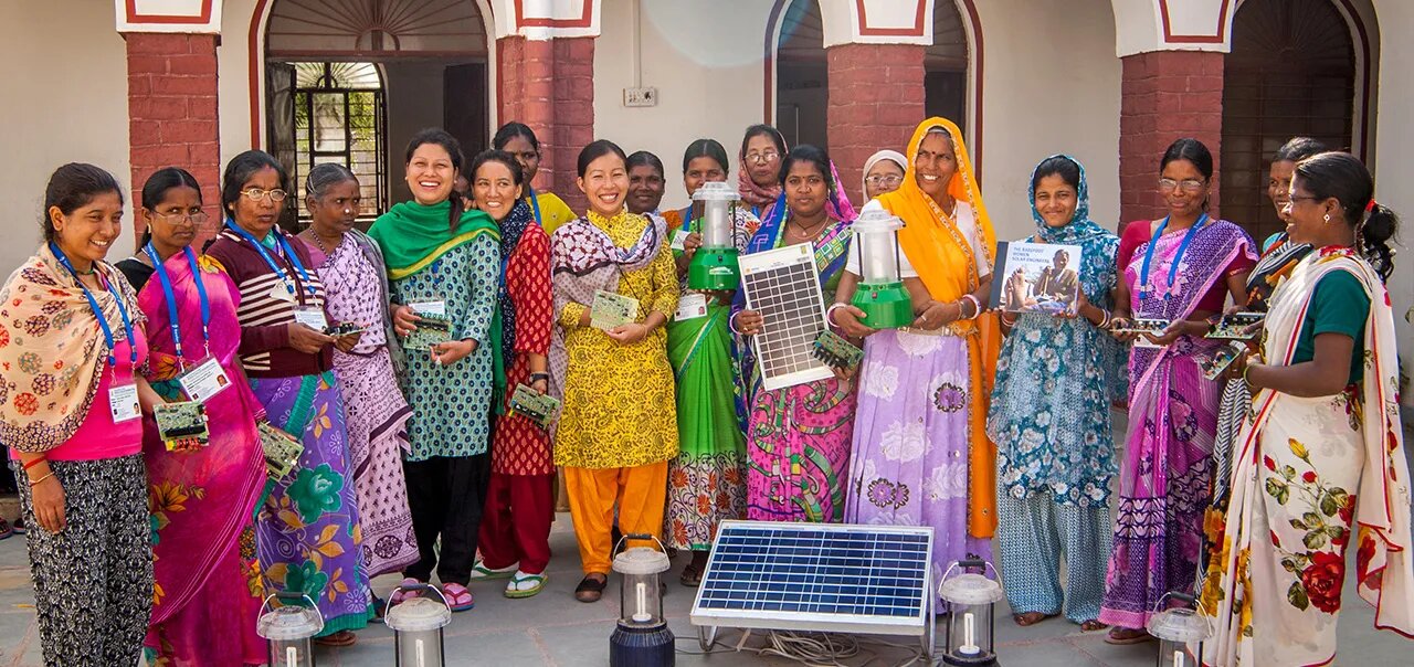 Group of women displaying solar cell panels, small circuits and electric lamps