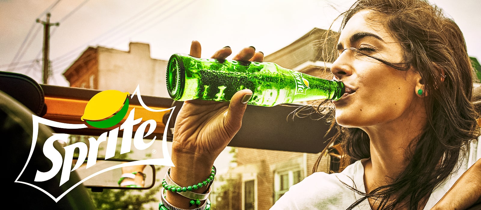 Woman drinking a bottle of Sprite with Sprite's logo on the side of the image