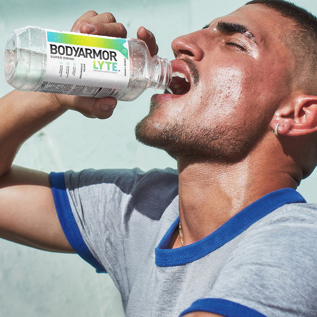 Chico sudando y bebiendo una botella de BodyArmour Lyte sabor Coco