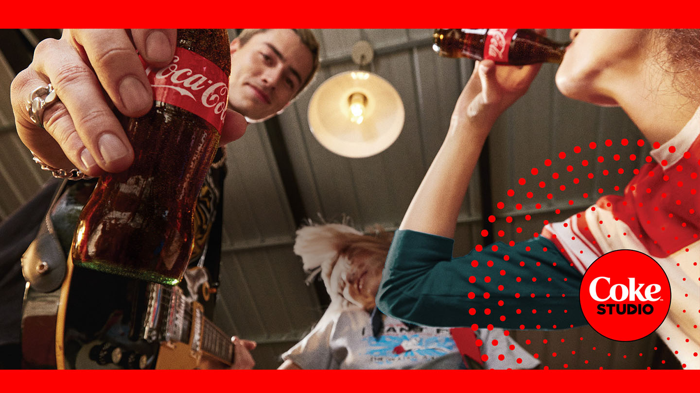 Tres jóvenes tocando la guitarra y bebiendo Coca-Cola