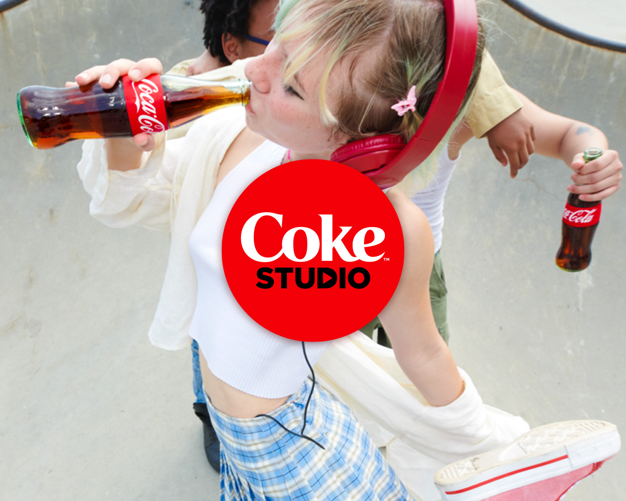 Chica con auriculares bebiendo Coca-Cola